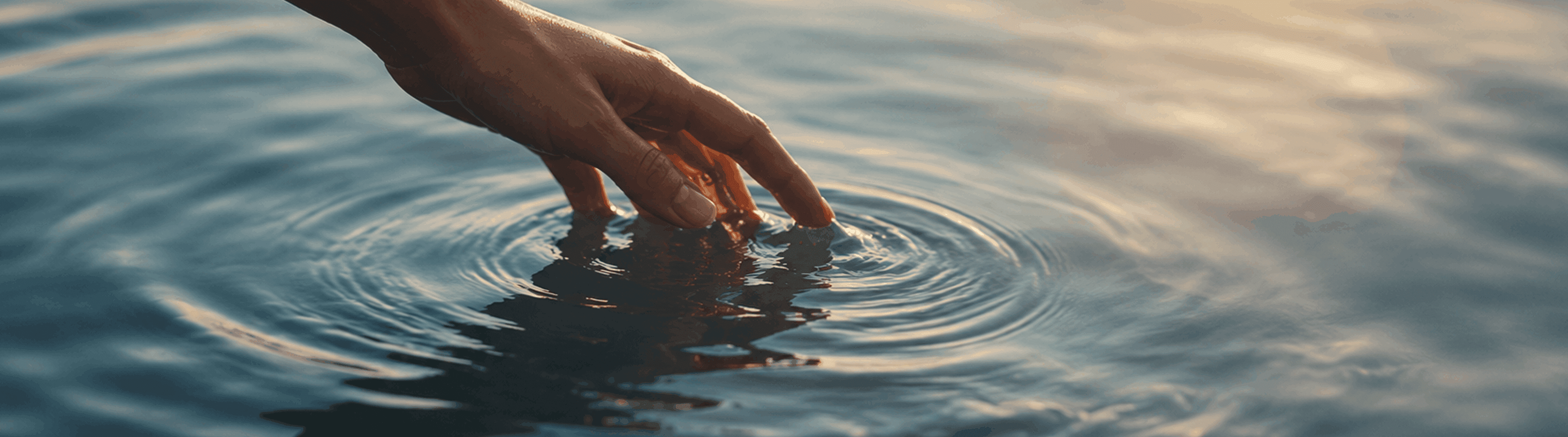 Photo - Vingers die het wateroppervlak raken en rimpelingen veroorzaken.